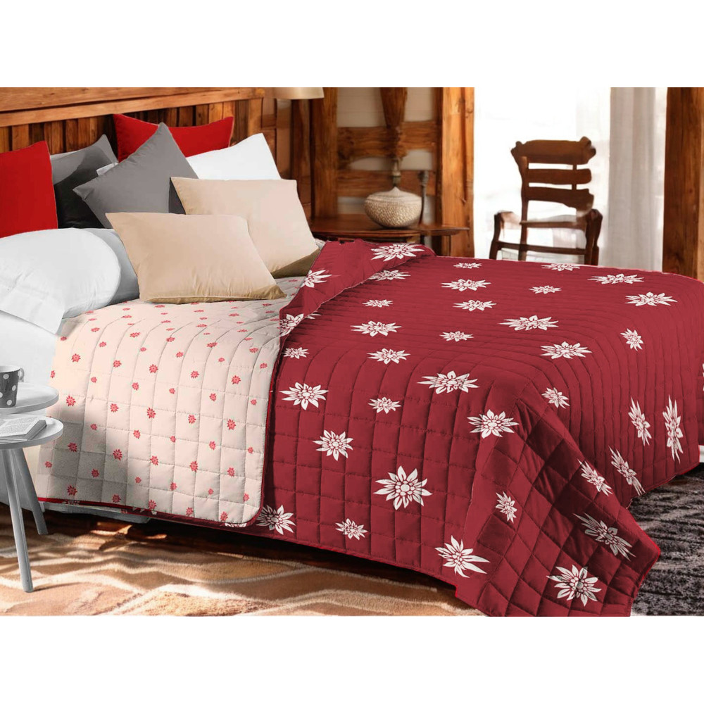 Couvre-lit matelassé Edelweiss rouge avec fleurs blanches sur lit rustique Couvre-lit matelassé Edelweiss rouge avec fleurs blanches sur lit rustique