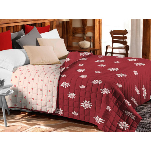 Couvre-lit matelassé Edelweiss rouge avec fleurs blanches sur lit rustique