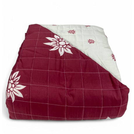 Rote Edelweiss Steppdecke mit weißen Blumen auf rustikalem Bett
